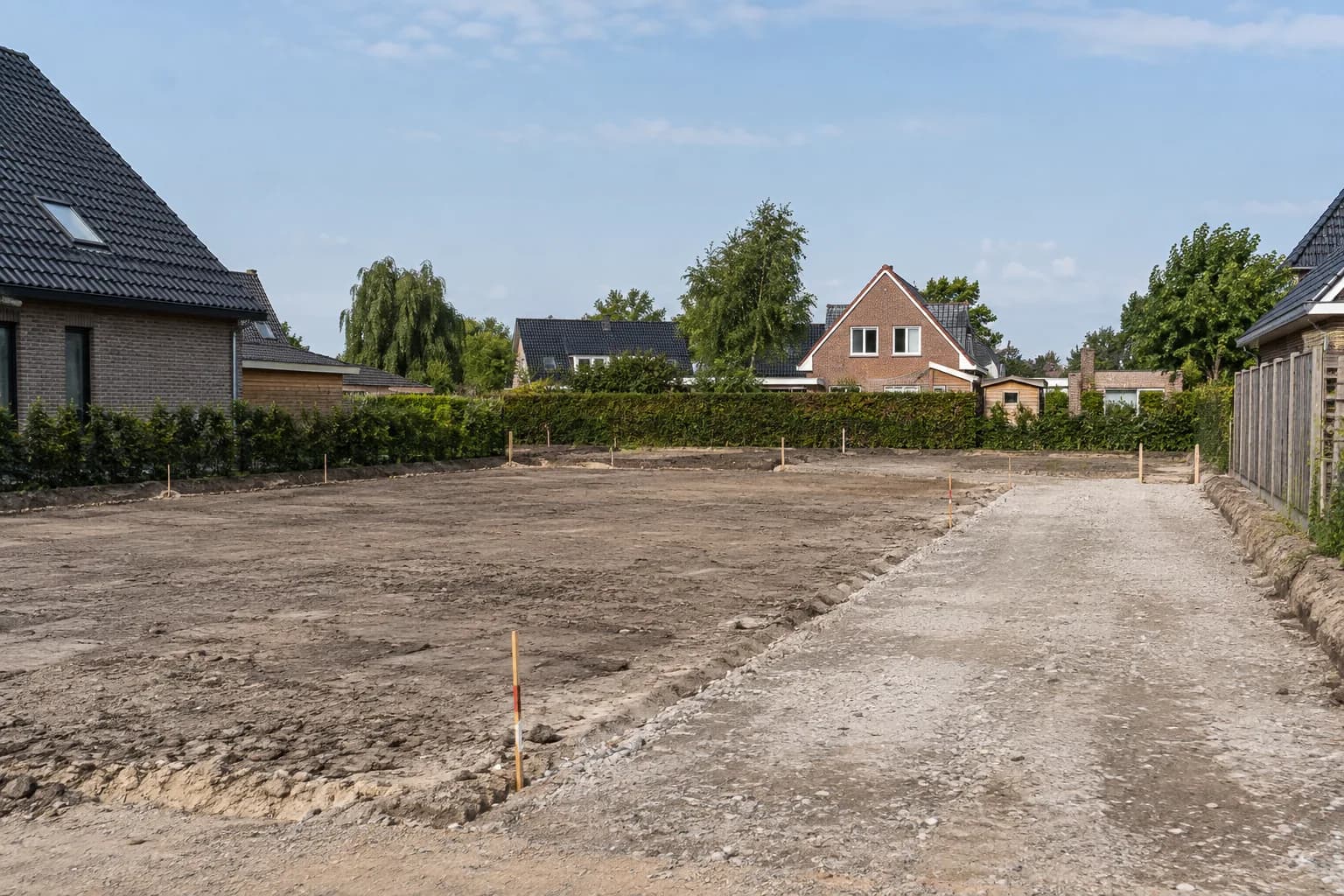 Geëgaliseerd bouwperceel met piketpalen en een verharde toegangsroute