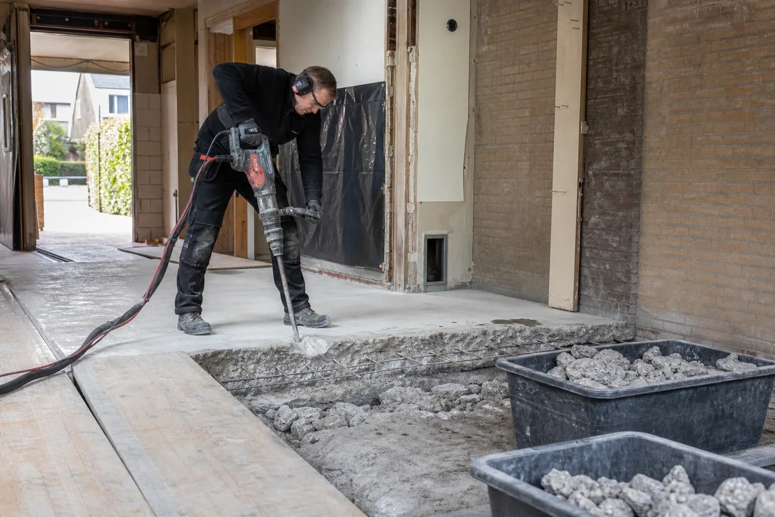 Vakman verwijdert gecontroleerd een gewapende betonvloer tijdens een woningrenovatie