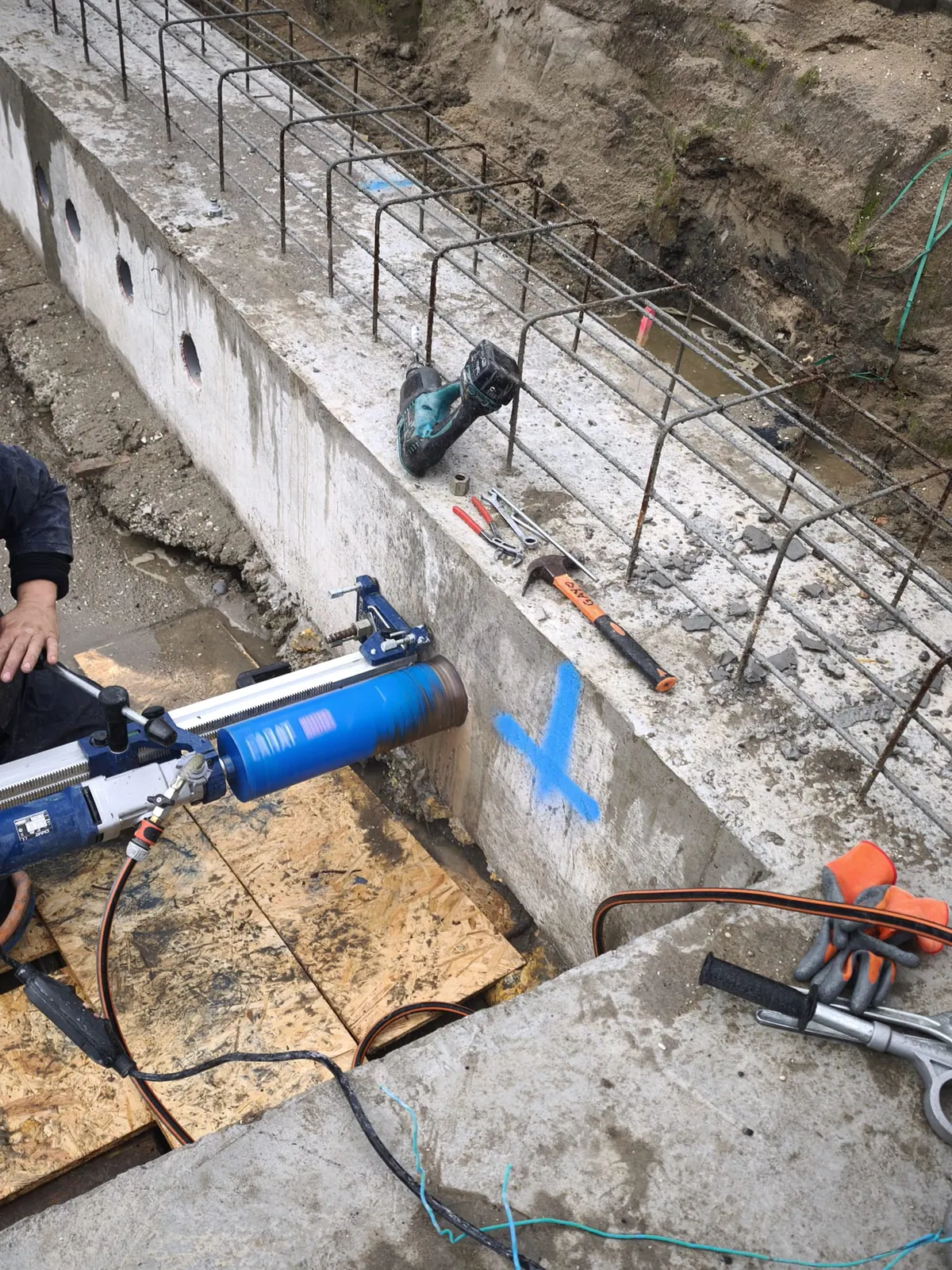 Diamantboormachine boort een ronde doorvoer in een betonnen funderingswand