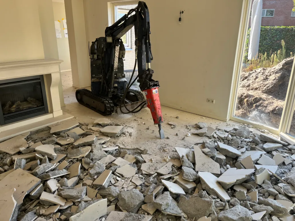 Minigraver breekt een bestaande vloer uit tijdens kleinschalig sloopwerk