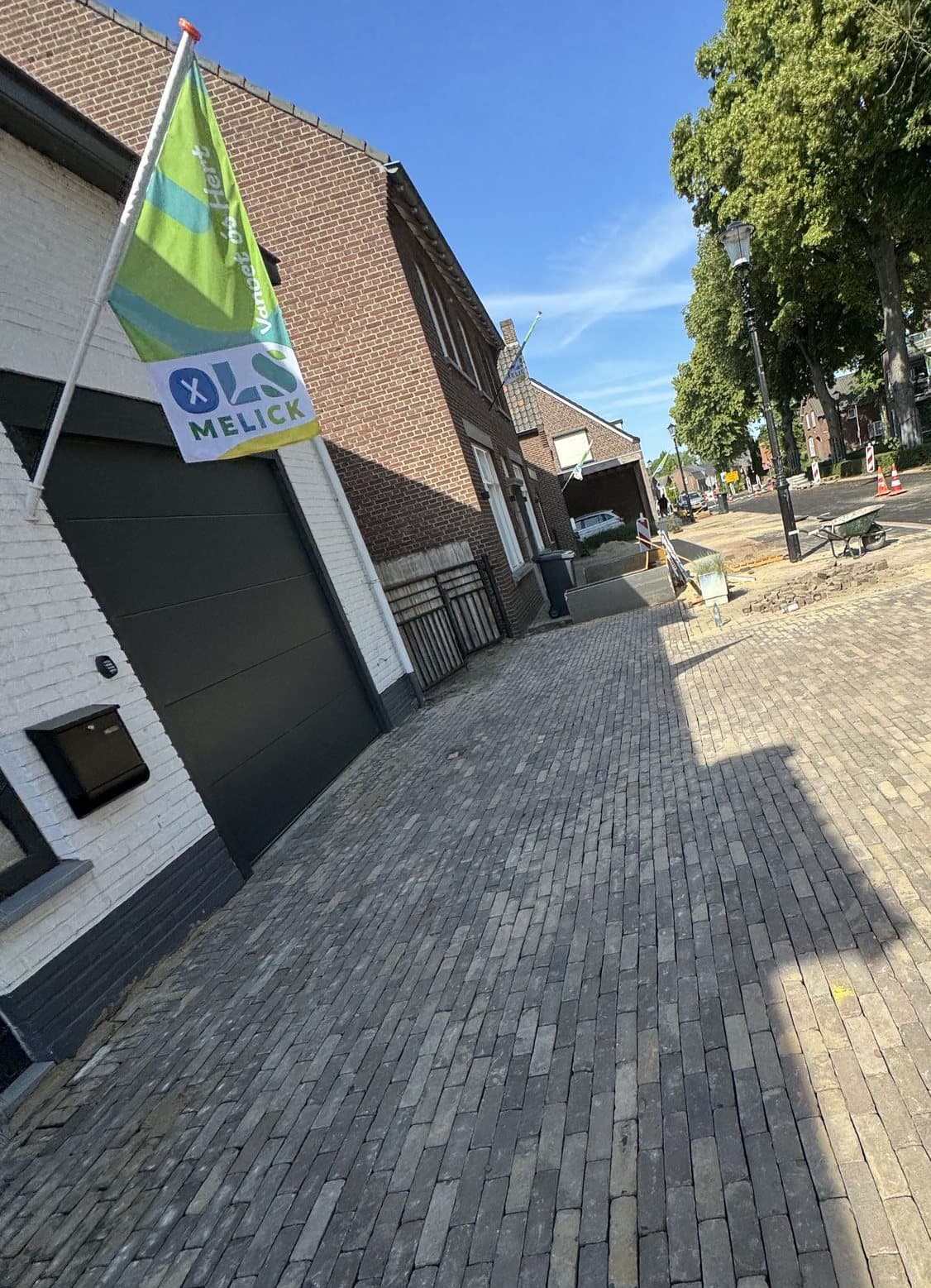 Nieuw bestrate oprit met donkere klinkers bij een woning in Melick